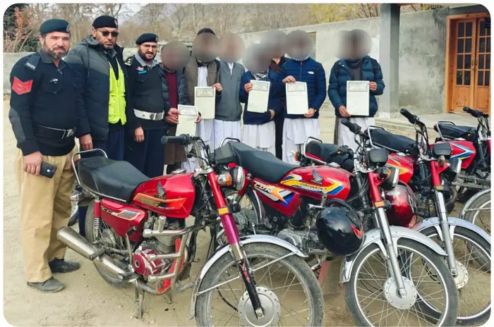 Underage bike drivers show undertakings submitted by their parents before being released by Chitral police, Dec 12, 2025.